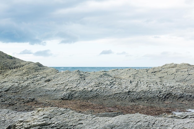 Rocky seashore made of columnar granite hardened lava resembling scales or cobblestone pavement coast of Kunashir island