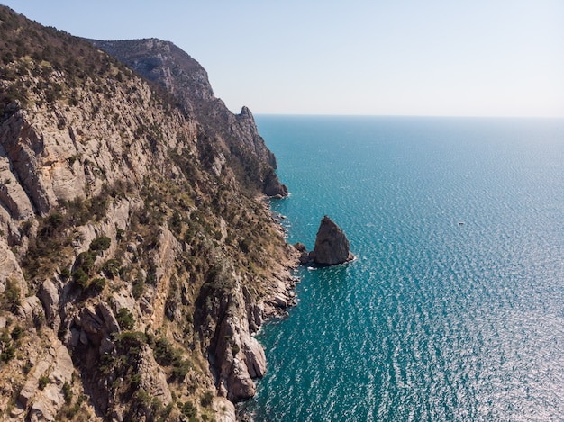 Rocky seashore top view. Huge steep cliffs and endless ocean. Freedom and travel.