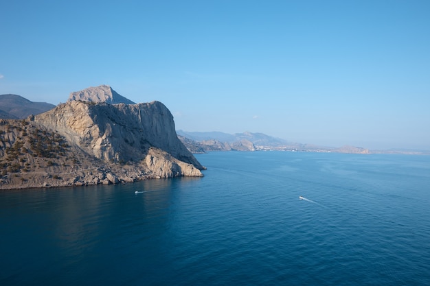 Фото Скалистый берег в море, дикий пляж и горы, скала уходит в воду, вид на море, дикий пейзаж