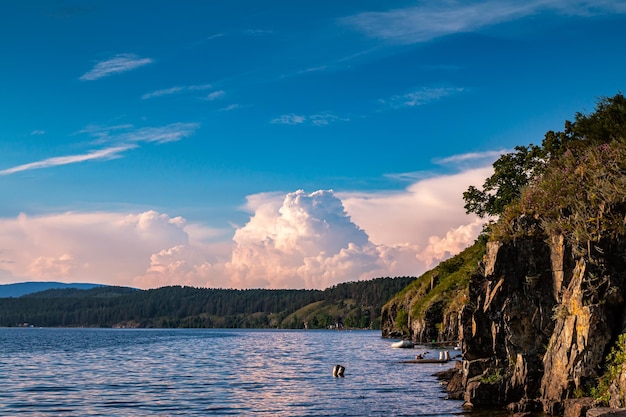 Скалистый берег живописного озера с красивыми кучевыми облаками в небе