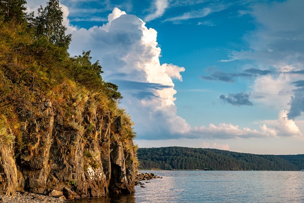 Rocky shore of a picturesque lake with beautiful cumulus clouds in the sky