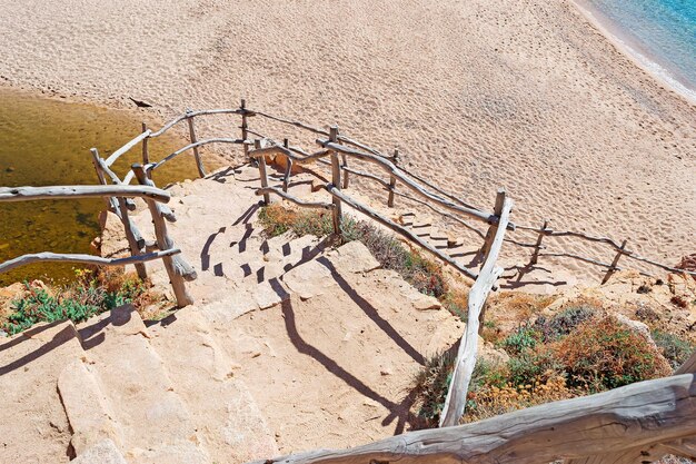 Rocky stairs and wooden banister to Costa Paradiso beach