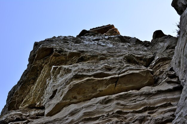 rocky wall of mountain isolated with blue sky on background, close-up