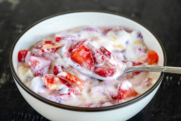 Rode aardbei en witte yoghurt brulee Fruitdessert bij het ontbijt met partjes perfect rijpe aardbeien van het seizoen close-up