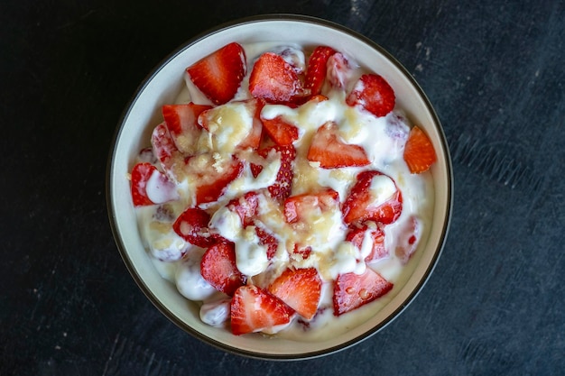 Rode aardbei en witte yoghurt brulee Fruitdessert bij het ontbijt met partjes perfect rijpe aardbeienclose-up in het seizoen