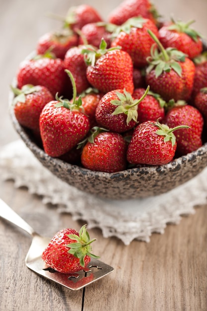 Foto rode aardbei in een kom op houten tafel