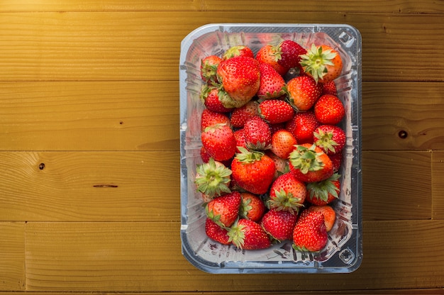 Foto rode aardbei in plastic doos op hout