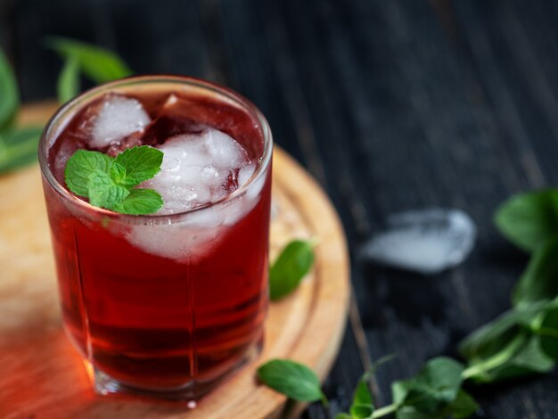 Rode alcoholische cocktail met ijs en munt in een glas