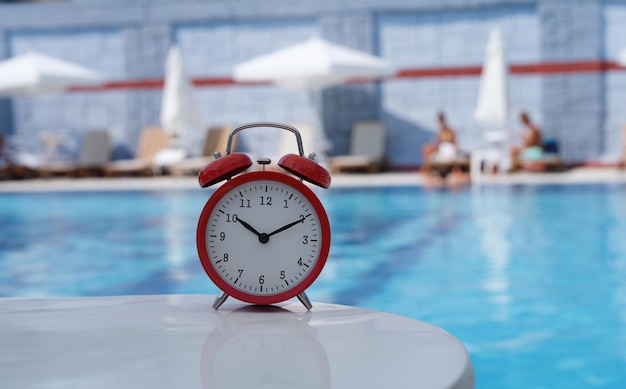 Rode analoge wekker met een wazige achtergrond van een ontspanningszwembad