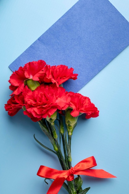 Rode anjer en blauwe envelop met ruimte voor tekst op een blauwe achtergrond bovenaanzicht