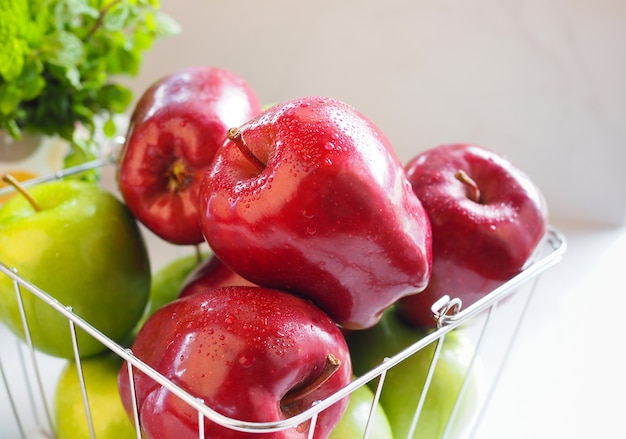 Rode appel en groene appel in de mand op witte tafel