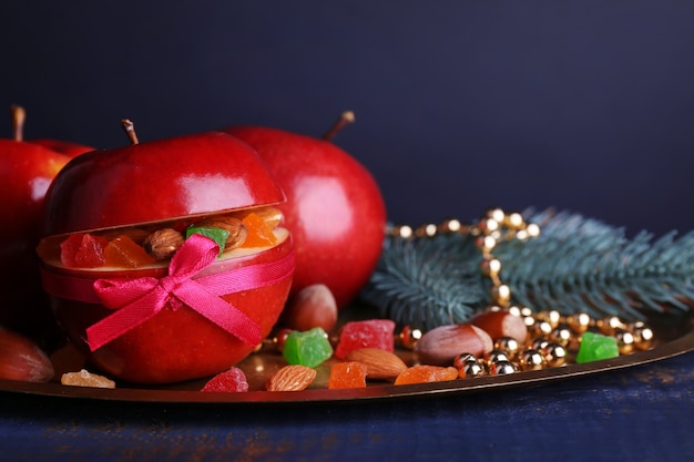 Rode appels gevuld met gedroogde vruchten op metalen dienblad op houten kleurentafel