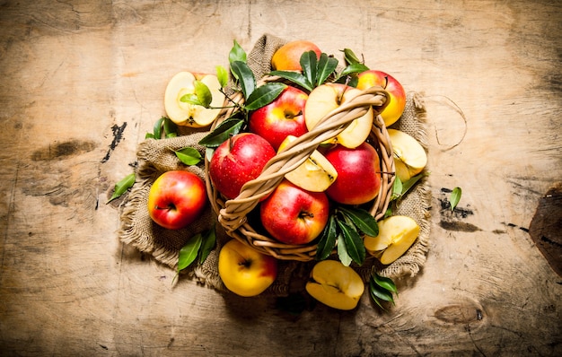 Rode appels in een oude mand met bladeren. Op een houten tafel. Bovenaanzicht