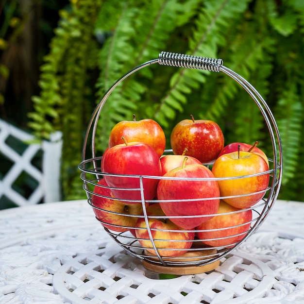 Rode appels in mand metaal op witte metalen tafel.