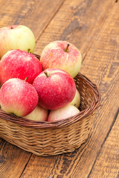 Rode appels in rieten mand op oude houten planken. Bovenaanzicht.