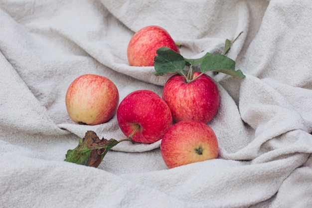 Rode appels liggen op een licht tafelkleed. Herfststemming, kleuren van herfsttrillingen, modieuze herfststijl, oogst