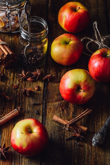 Rode appels met verspreide kruidnagel, kaneel en anijsster. Ingrediënten voor het bereiden van glühwein. Verticale oriëntatie.