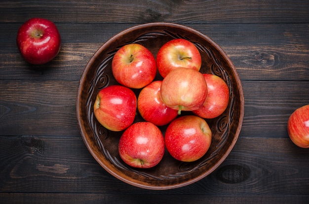 Rode appels op een donkere rustieke achtergrond in een kom klei. Plat leggen.