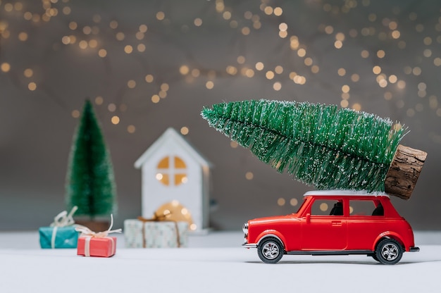 Rode auto met een kerstboom op het dak. Tegen de achtergrond van het huis. Concept rond het thema Kerstmis en Nieuwjaar.