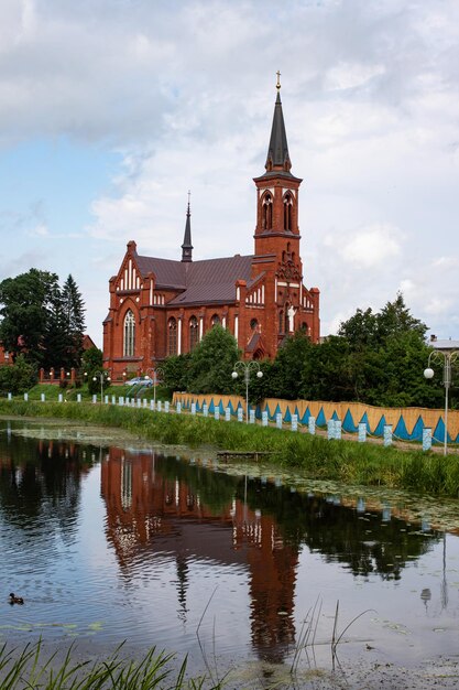 Rode bakstenen kerk aan de rivier en bewolkte hemel