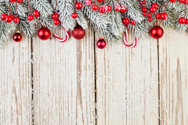 Rode bevroren hulst bessen kerstballen en groene spar tak op witte houten achtergrond kaart kerst grens Minimal Xmas plat lag bovenaanzicht op houtstructuur met kopie ruimte