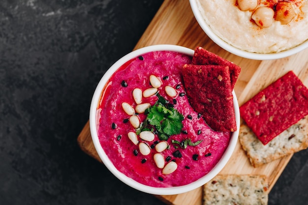 Rode biet Bieten Hummus met knäckebröd Gezonde veganistische dip op donkere stenen achtergrond kopie ruimte