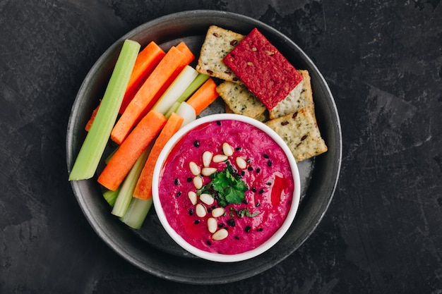Rode biet Bieten Hummus met verse groenten en knäckebröd Gezonde veganistische dip op donkere stenen achtergrond kopie ruimte