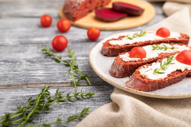 Rode bietenbroodsandwiches met roomkaas en tomaten op grijze houten achtergrond Zijaanzicht selectieve focus