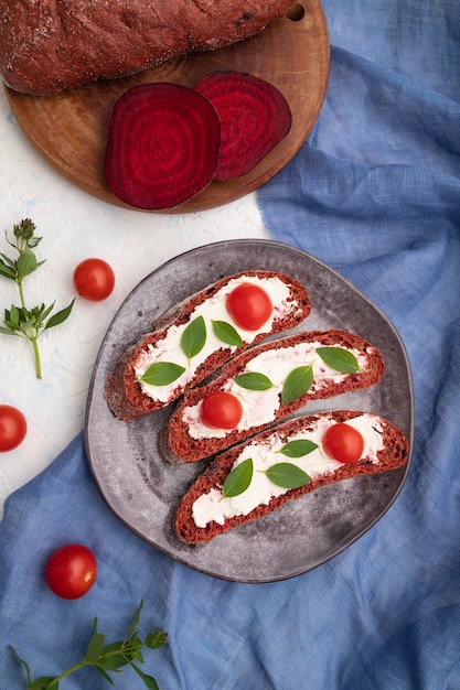 Rode bietenbroodsandwiches met roomkaas en tomaten op wit