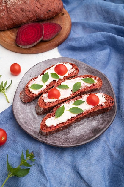 Rode bietenbroodsandwiches met roomkaas en tomaten op witte betonnen achtergrond Zijaanzicht