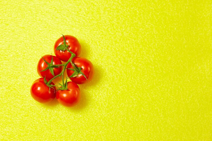 Rode biologische tomaten op een groene tak op een gele achtergrond