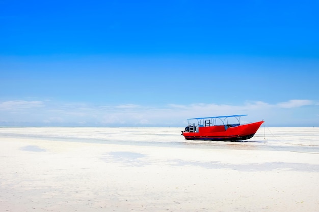 Rode boot op het strand van Zanzibar op de blauwe hemelachtergrond Afrika Tanzania