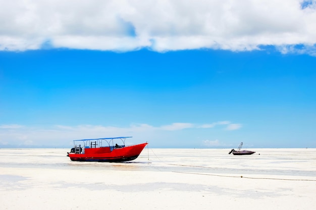 Rode boot op het strand van Zanzibar op de blauwe hemelachtergrond Afrika Tanzania