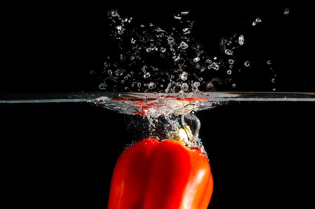 Rode chili peper in het water gegooid. Zwarte achtergrond om de versheid en helder te zien