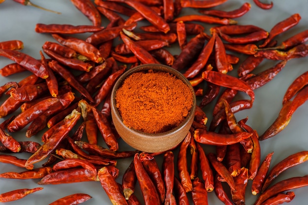 Rode chilipoeder of paprika in een houten kom op een donkere achtergrond, close-up. Koken ingrediënten, smaak.