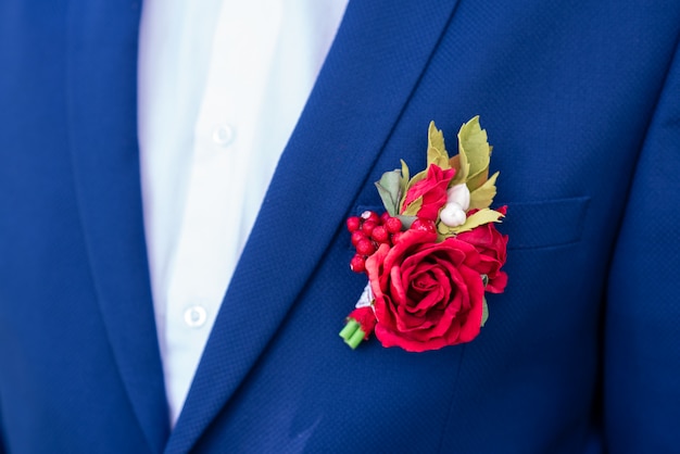 Rode corsages op een blauwe jas.