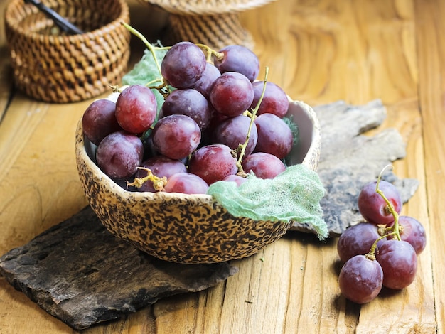 Rode druif vruchten in kom op houten tafel. Stilleven concept
