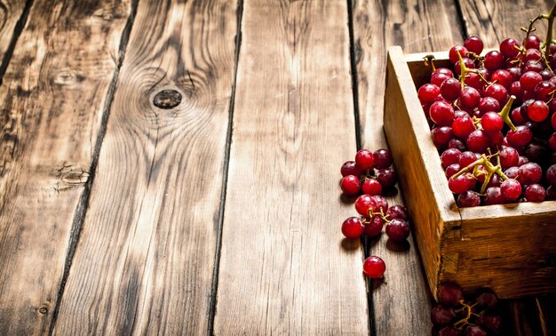 Rode druiven in een oude doos. Op houten achtergrond.