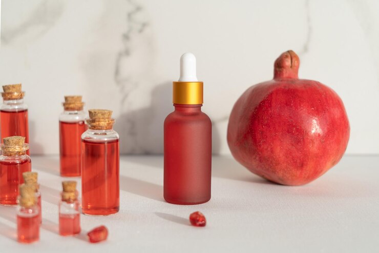 Rode druppelflesjes granaatappelserum of olie voor gezicht en lichaam op een witte achtergrond