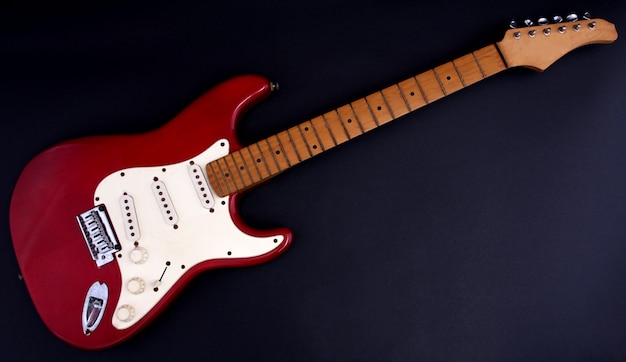 Foto rode elektrische gitaar met een zwarte achtergrond.