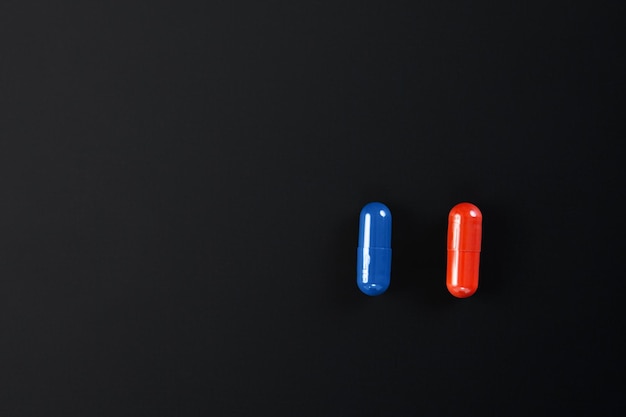 Rode en blauwe pillen geïsoleerd op zwarte achtergrond met uitknippad