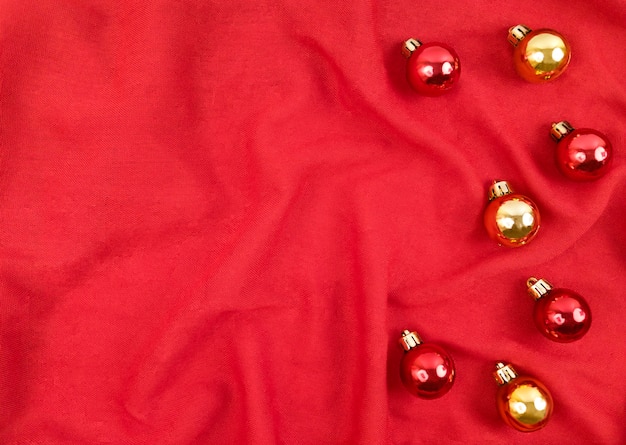 Rode en gouden kerstballen op een rode textiel achtergrond.