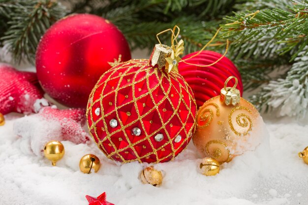 Rode en gouden Kerstmisbal in sneeuw onder spar