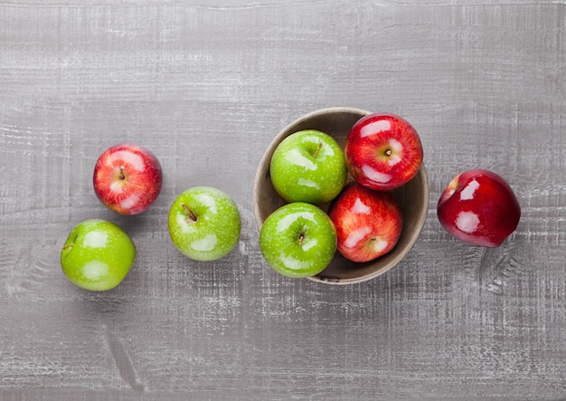 Rode en groene appels in houten kom op houten bord