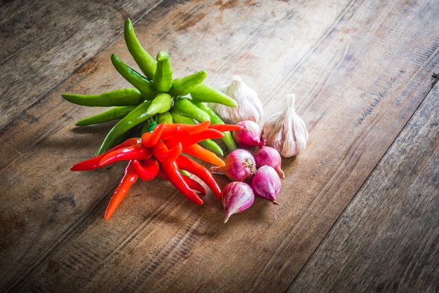 Rode en groene chili peper en rode ui en knoflook op een oude houten achtergrond