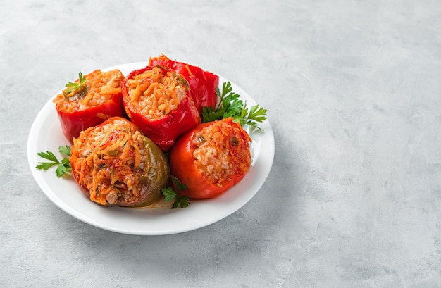 Rode en groene paprika gevuld met kalkoenrijst en groenten op een wit bord met verse kruiden