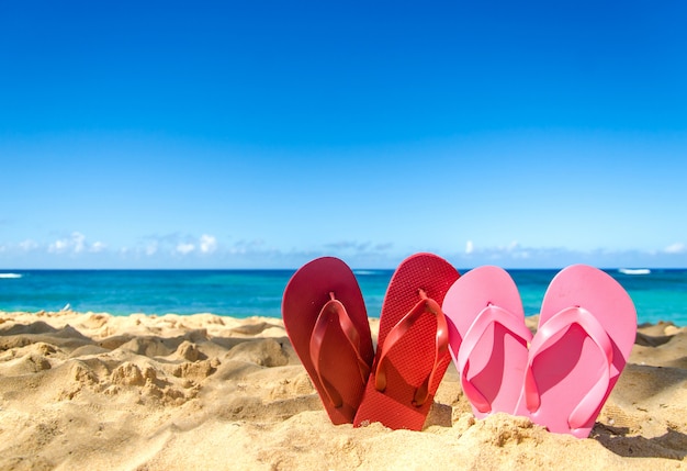 Rode en roze flip flops op het zandstrand