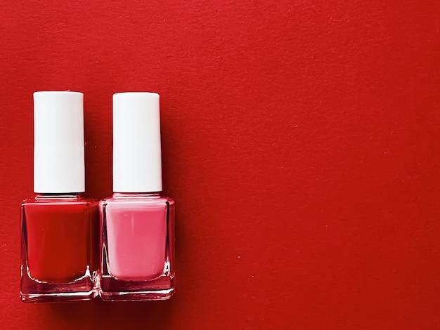Rode en roze nagellakflessen op rode achtergrond manicure en schoonheidscosmetica concept