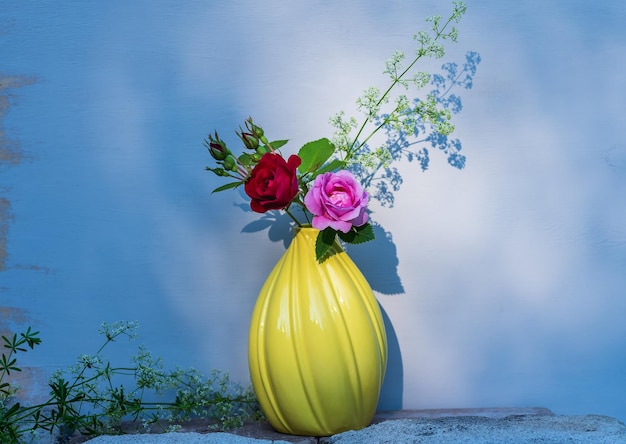 Rode en roze roos geplukt uit een tuin met een decoratieve gele vaas