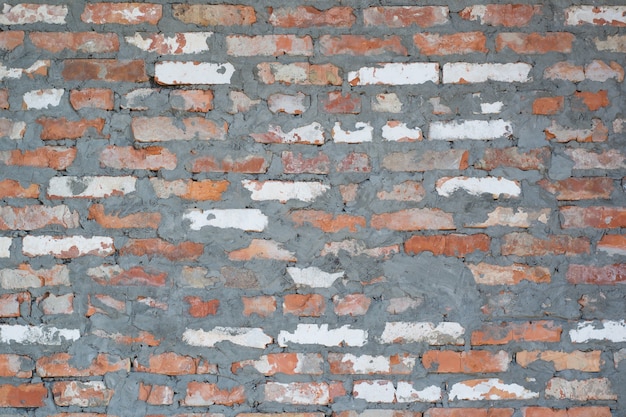 Rode en witte bakstenen muur met stukjes cement